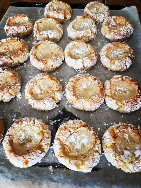 Tray of gluten-free almond and local mandarin crinkle cookies dusted in icing sugar, fresh from the oven