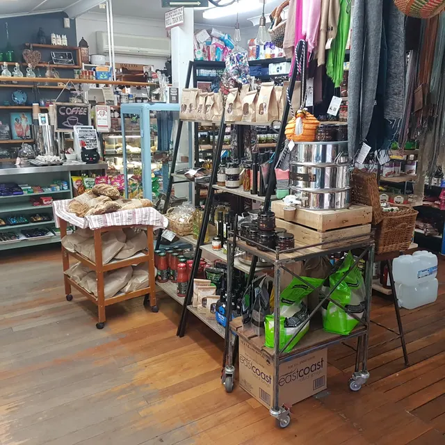 Inside the store: a pantry trolley, cakes and bread on display, grocery shelves.